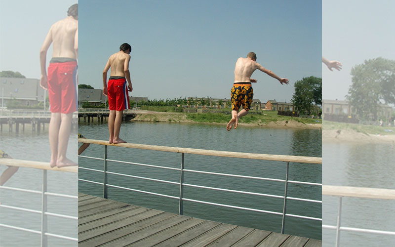 jongens springen van brug in Rietplas
